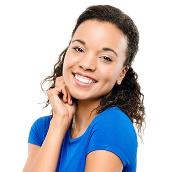 Lady with short curly hair and wearing a blue blouse is smiling while her right hand is under her right cheek