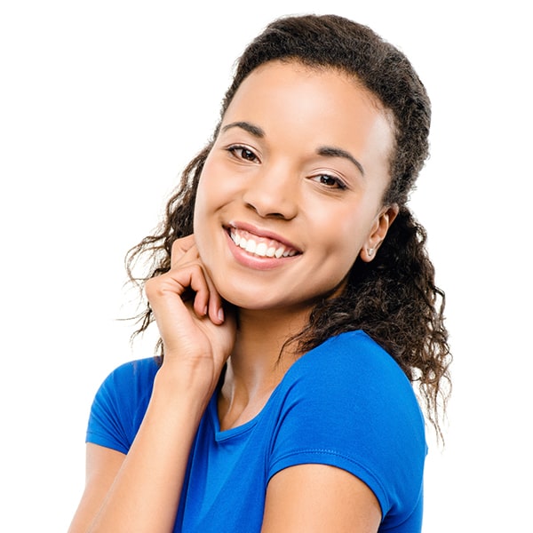 Lady with short curly hair and wearing a blue blouse is smiling while her right hand is under her right cheek