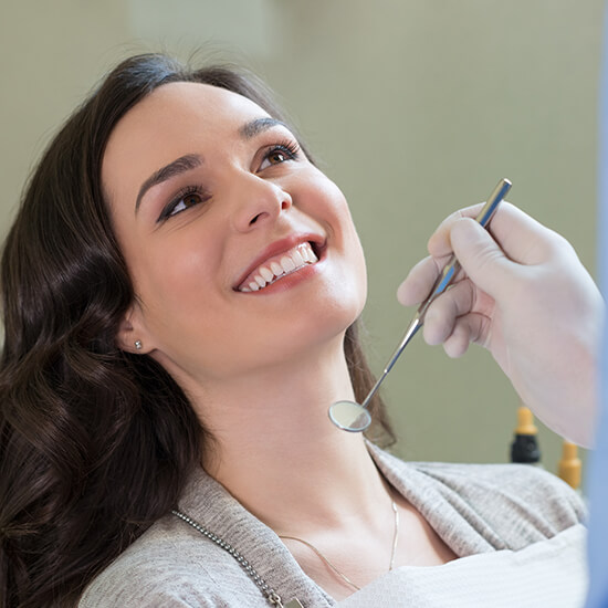 A smiling lady and a hand holding a dental instrument