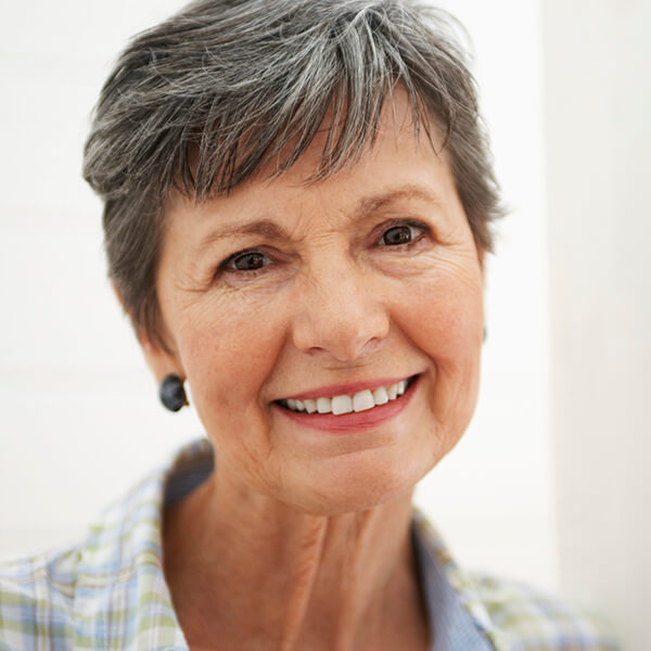 an old woman with a grayish black  short hair showing her smile 