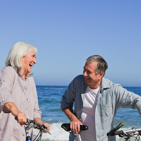 A man and a woman with laughing smile while holding on their bicycle