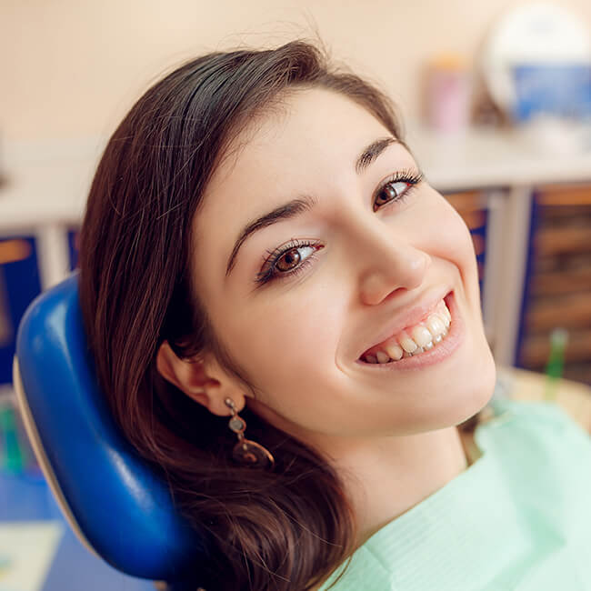 A smiling lady is lying on a dental chair and is looking to her right