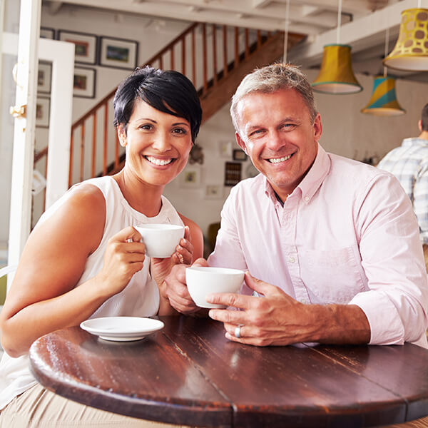 A couple is smiling while holding on a white cup