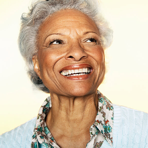 A lady with short curly hair smiling on a light background
